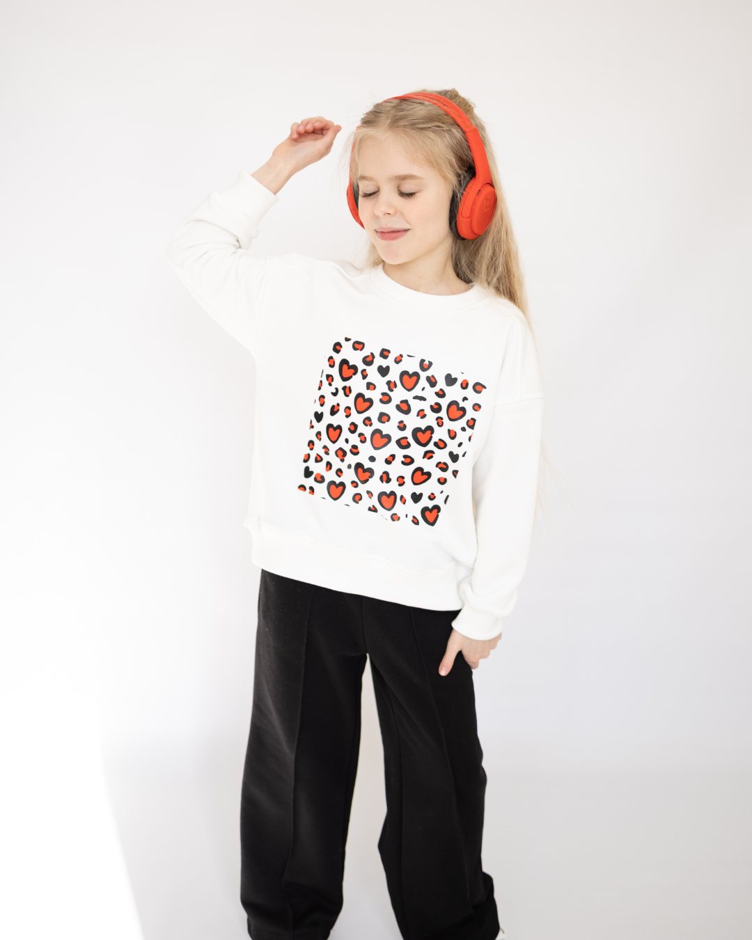 Girl wearing white sweatshirt with red heart pattern