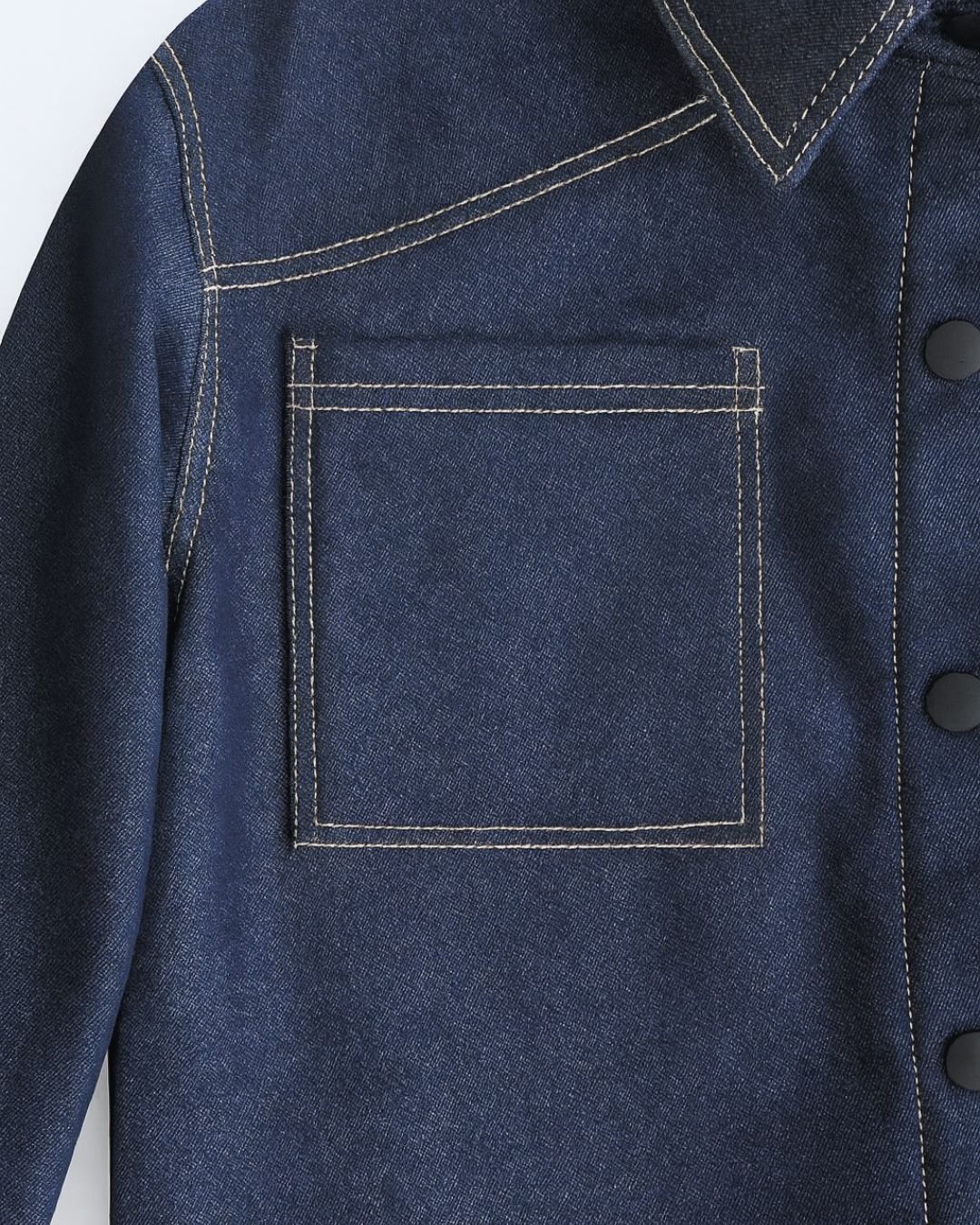 Denim jacket detail: square chest patch pocket with double topstitching, collar and snap placket, dark indigo