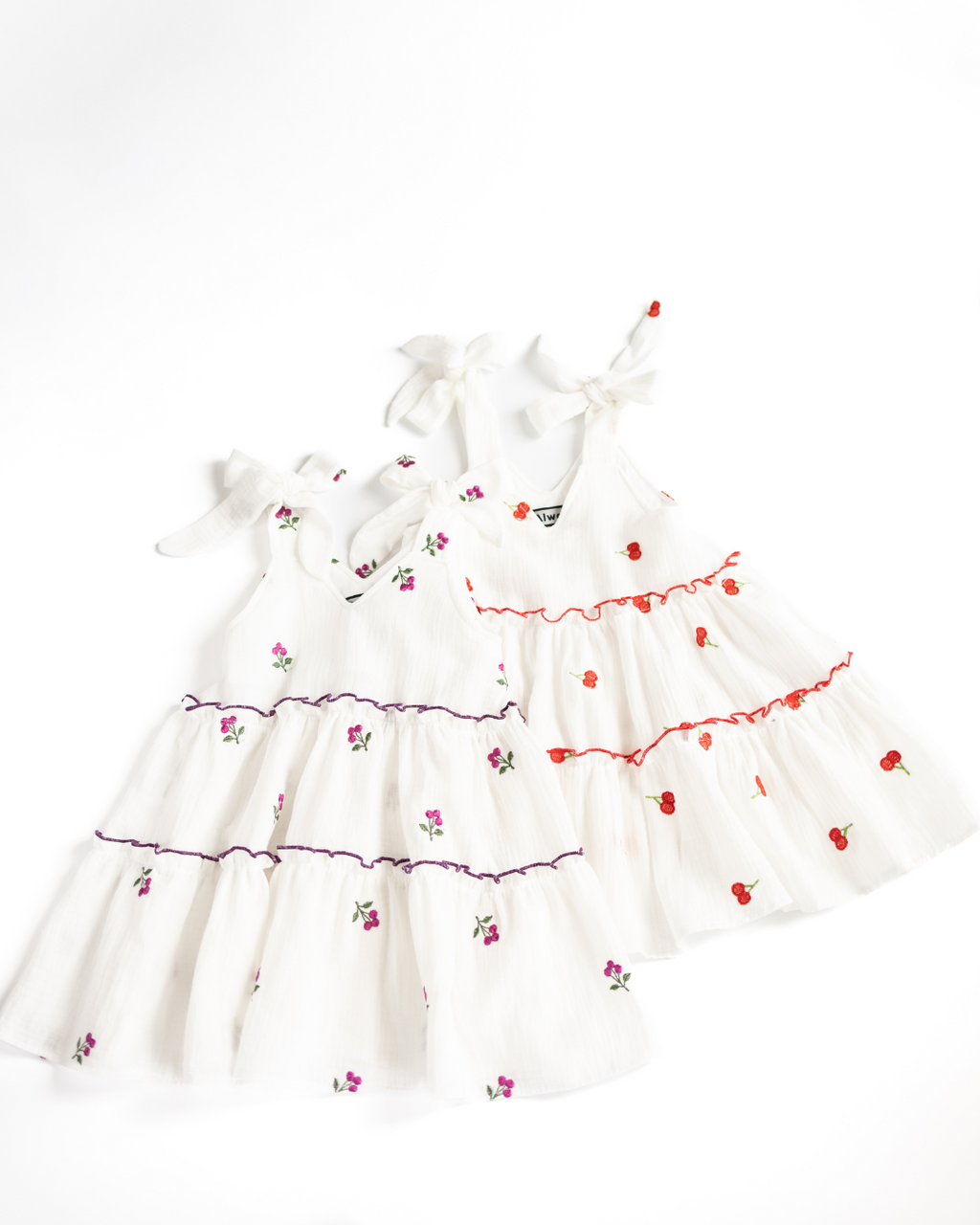 Two embroidered muslin dresses for girls side by side on white background – Alwair Kids