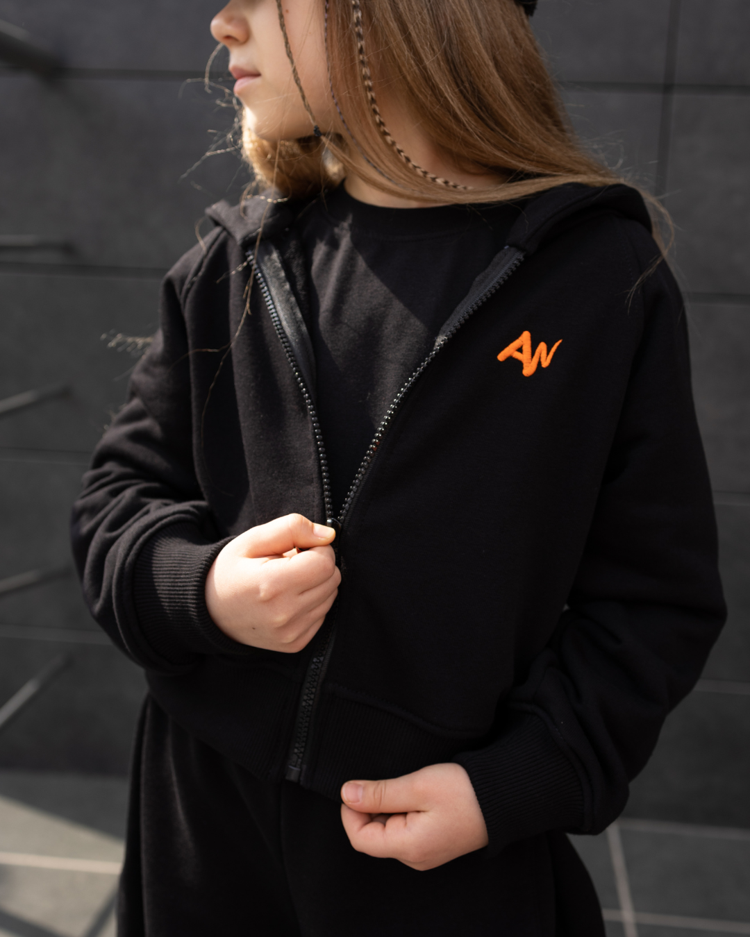 Girl modeling black hoodie with orange AW logo