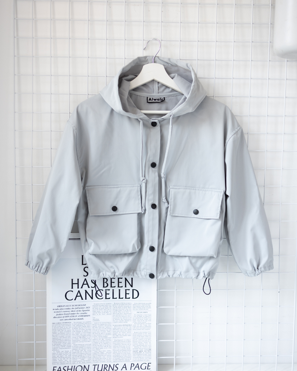 Front view of grey kids windbreaker jacket with hood and pockets