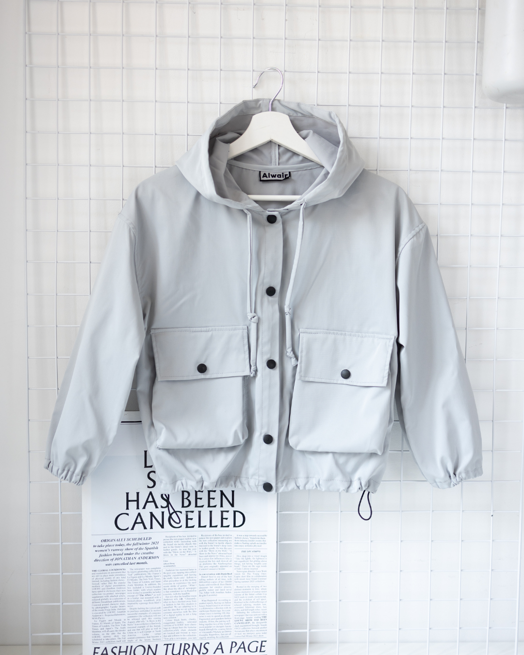 Front view of grey kids windbreaker jacket with hood and pockets