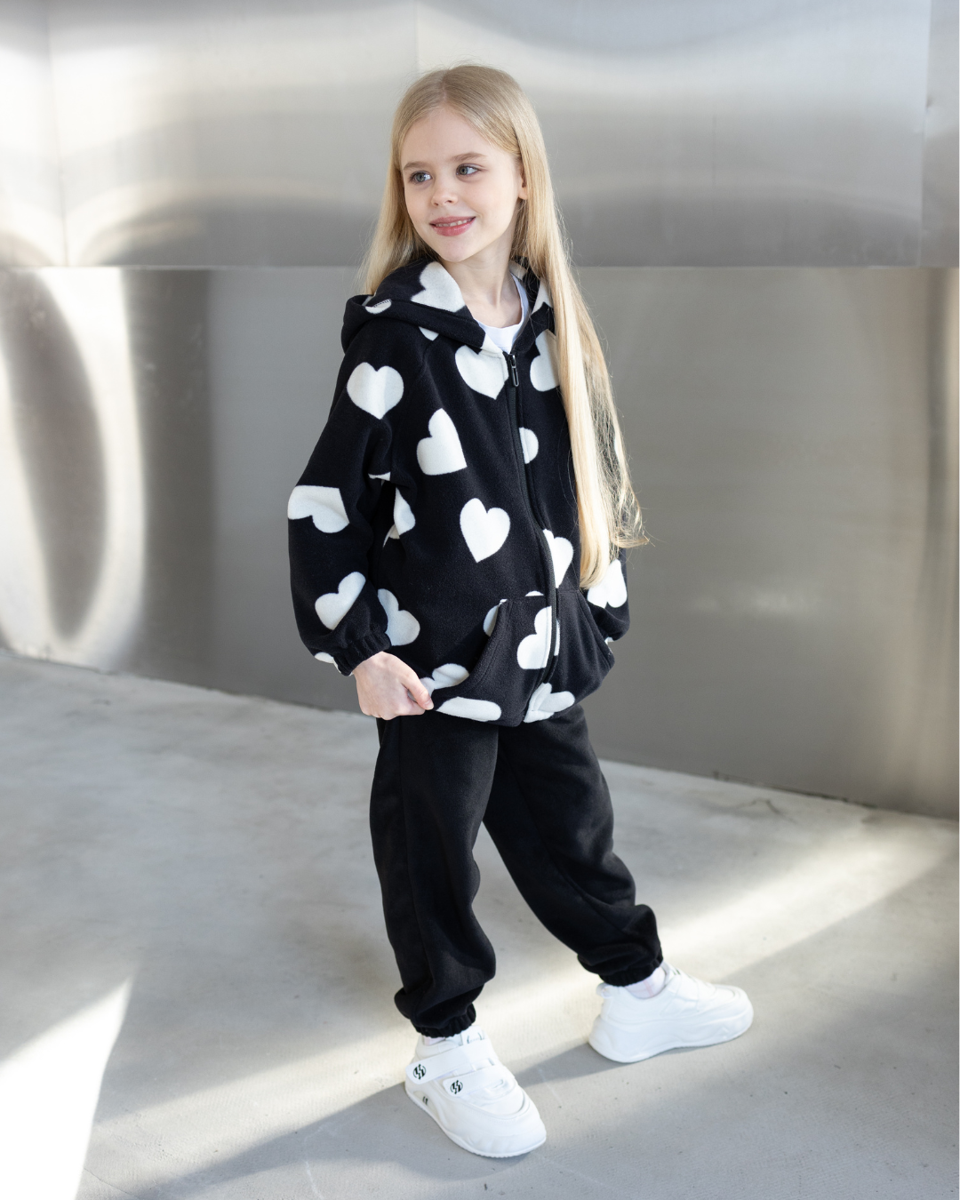 Girl wearing Alwair Kids fleece zip hoodie with white heart print front view


