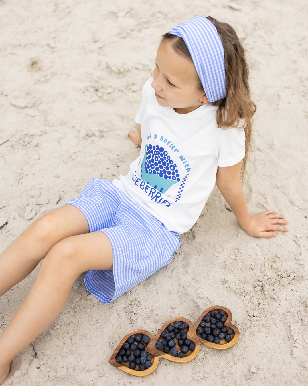 Girl wearing Blueberries cotton outfit from Alwair Kids sitting on the beach