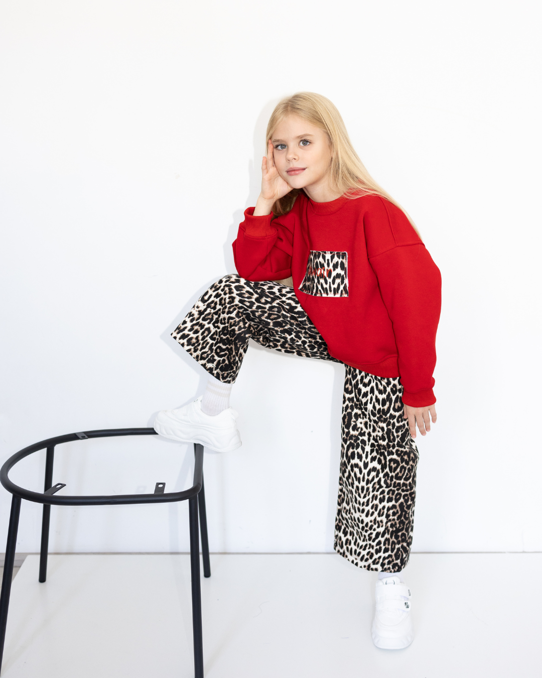 Girl in red Alwair Kids sweatshirt with leopard print pocket standing on chair