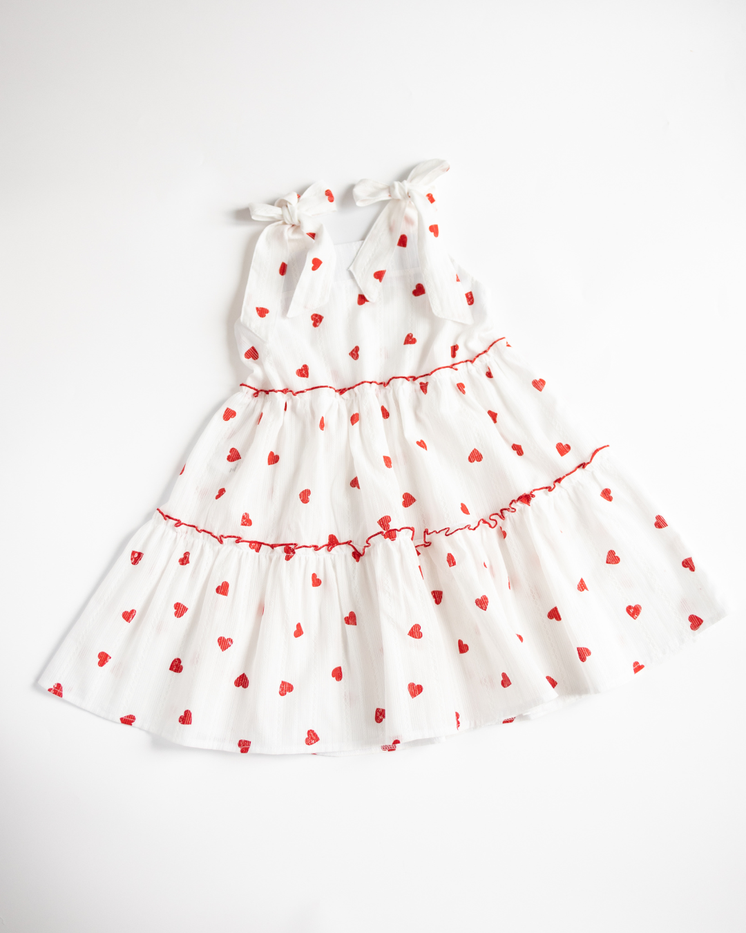 Flat lay of white heart print sundress with ruffle tiers – Alwair Kids summer dress