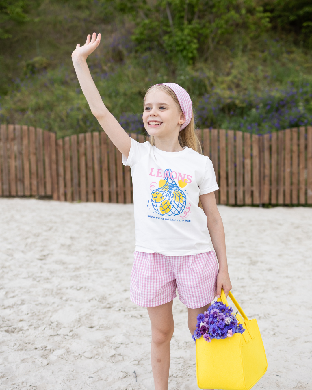 Girl waving in Lemons summer set by Alwair Kids with headscarf and gingham shorts