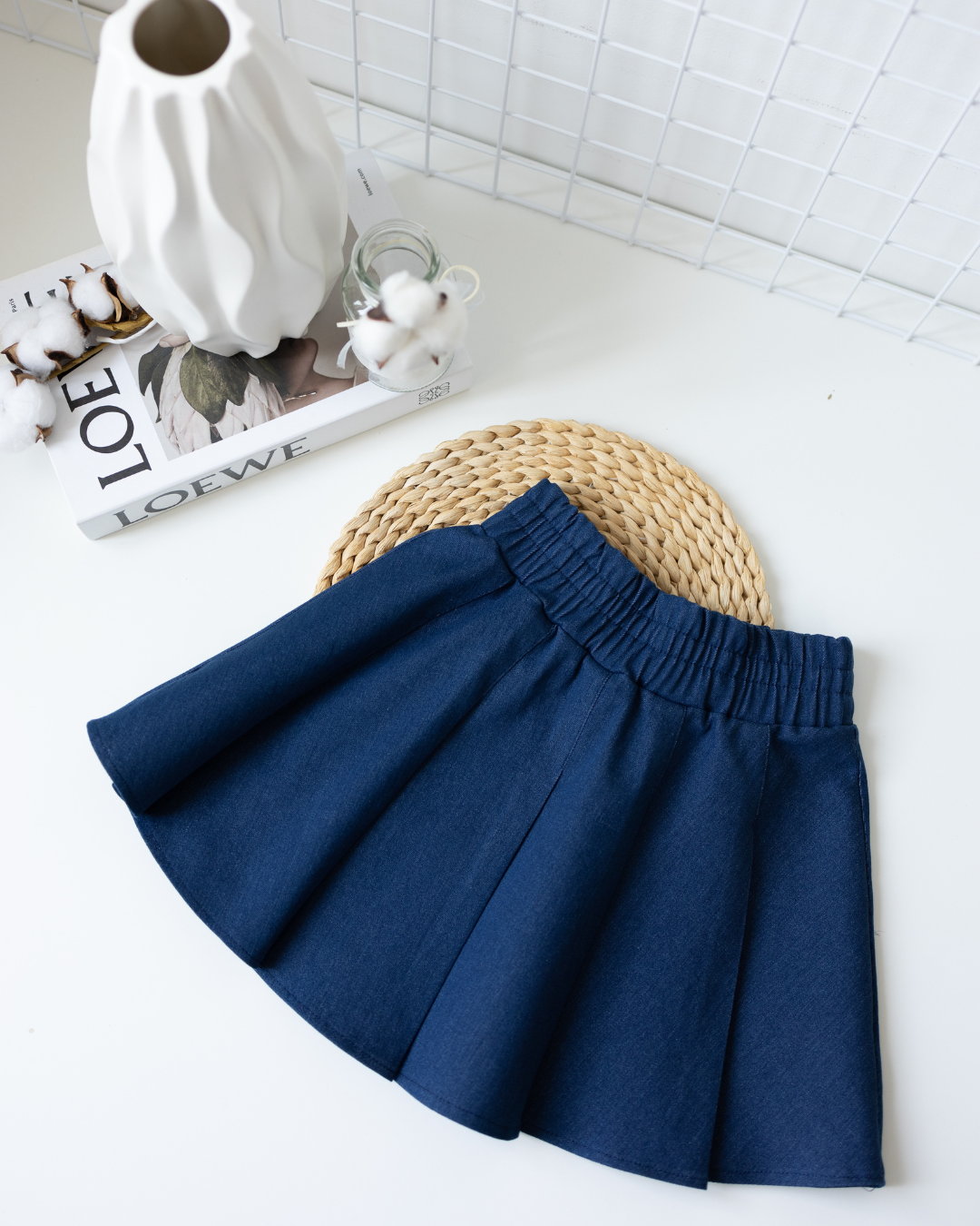 Flat lay of pleated navy denim tennis skirt for girls by Alwair Kids