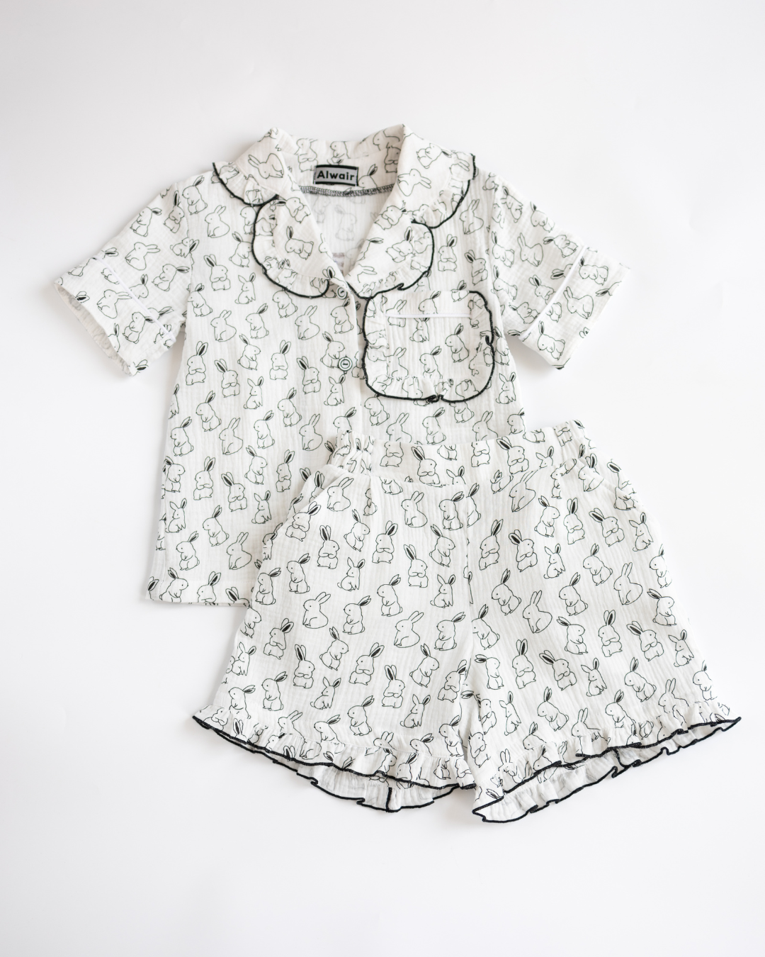 Flat lay of girls muslin pajama set with bunny print and cute sleep-themed props