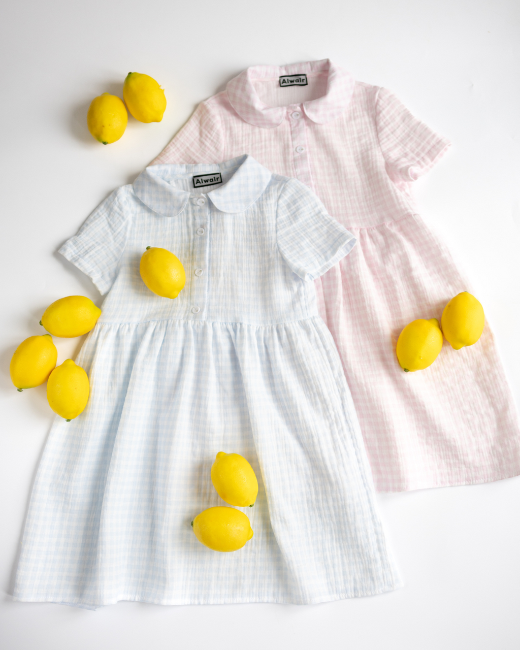 Blue and pink muslin dresses for girls by Alwair Kids laid flat on white background