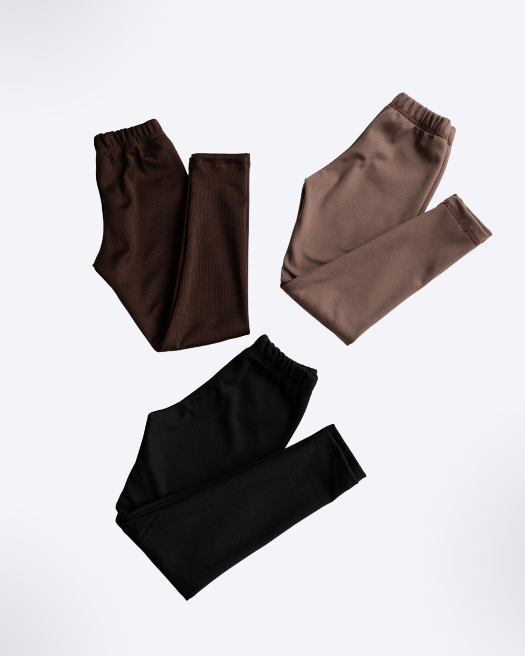 Three pairs of ribbed knit leggings in brown beige and black on white background - Alwair Kids