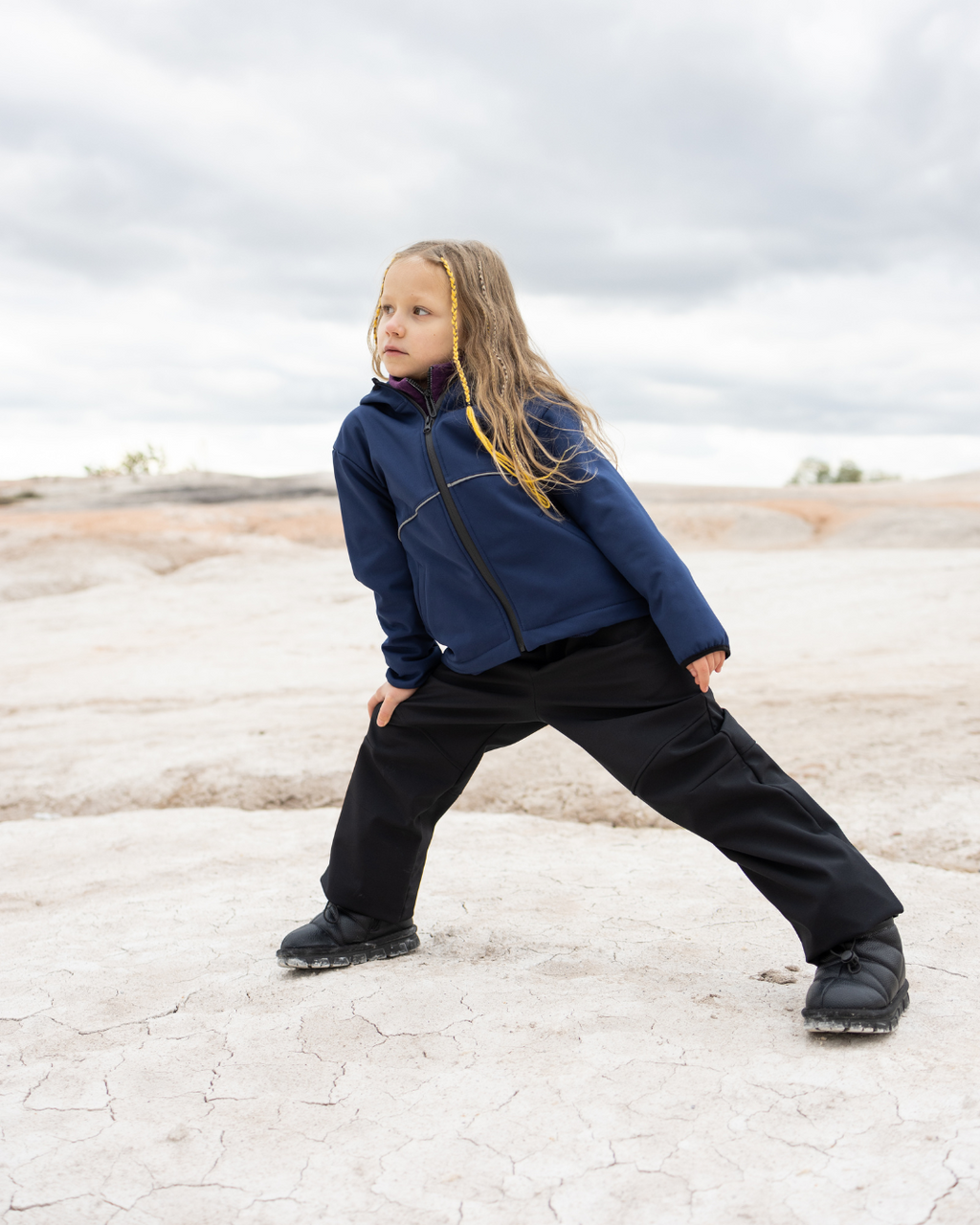 Child stretching in navy softshell jacket by Alwair Kids for active outdoor play

