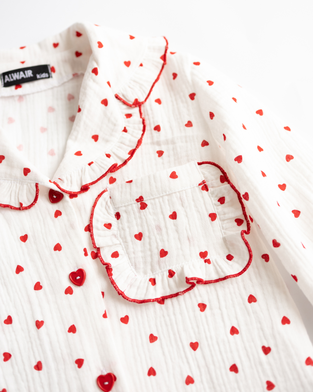 Close-up of pajama pocket with ruffle details and red heart buttons