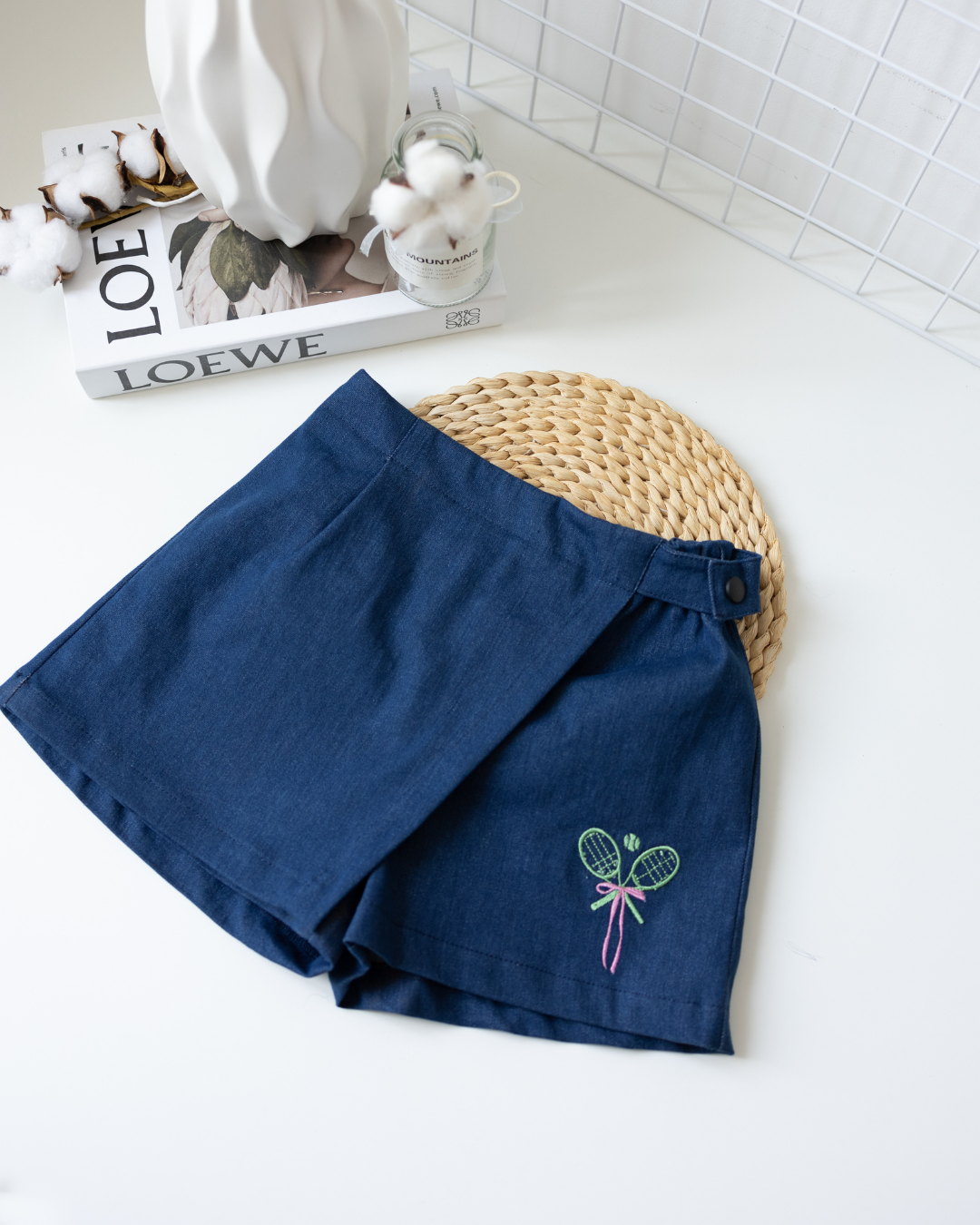Flat lay of girls' navy blue denim skort with tennis embroidery by Alwair Kids