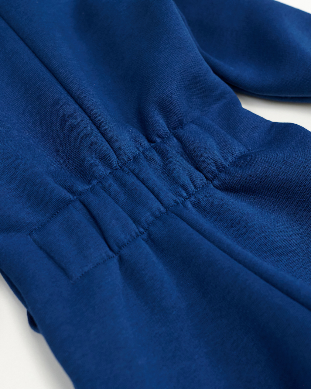 Close-up of elastic back on blue kids fleece jumpsuit showing stretch feature