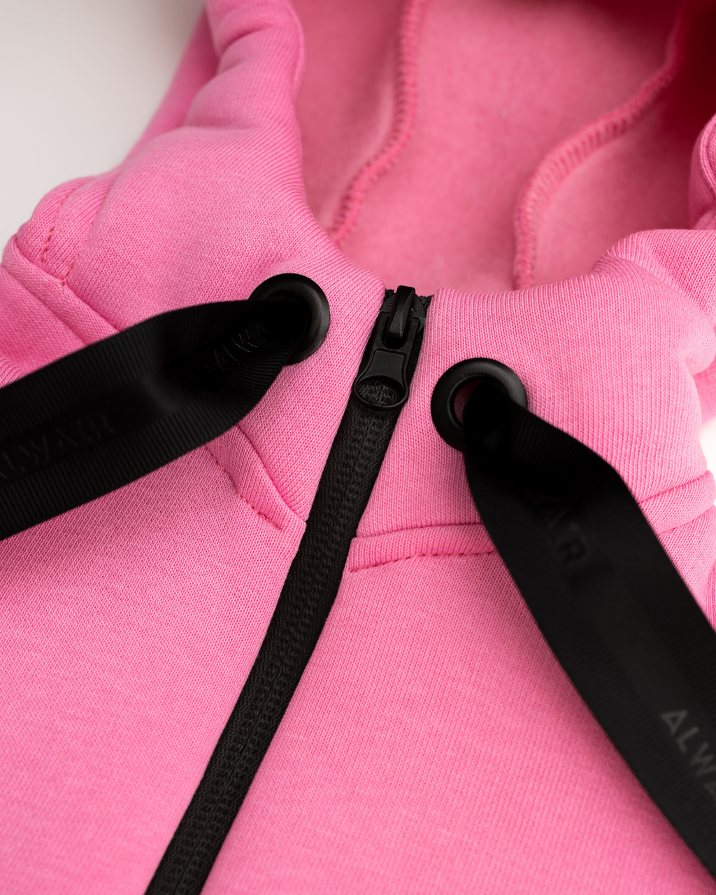 Close-up of zipper and hood stitching on light pink fleece kids jumpsuit