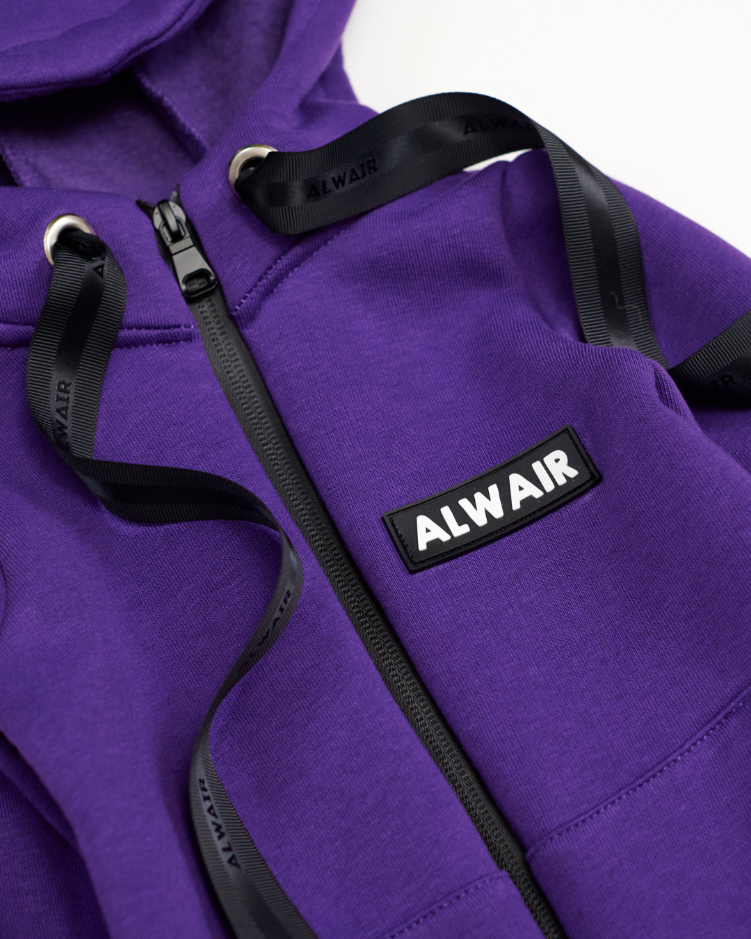 Close-up of Alwair logo and zipper on purple fleece jumpsuit for kids