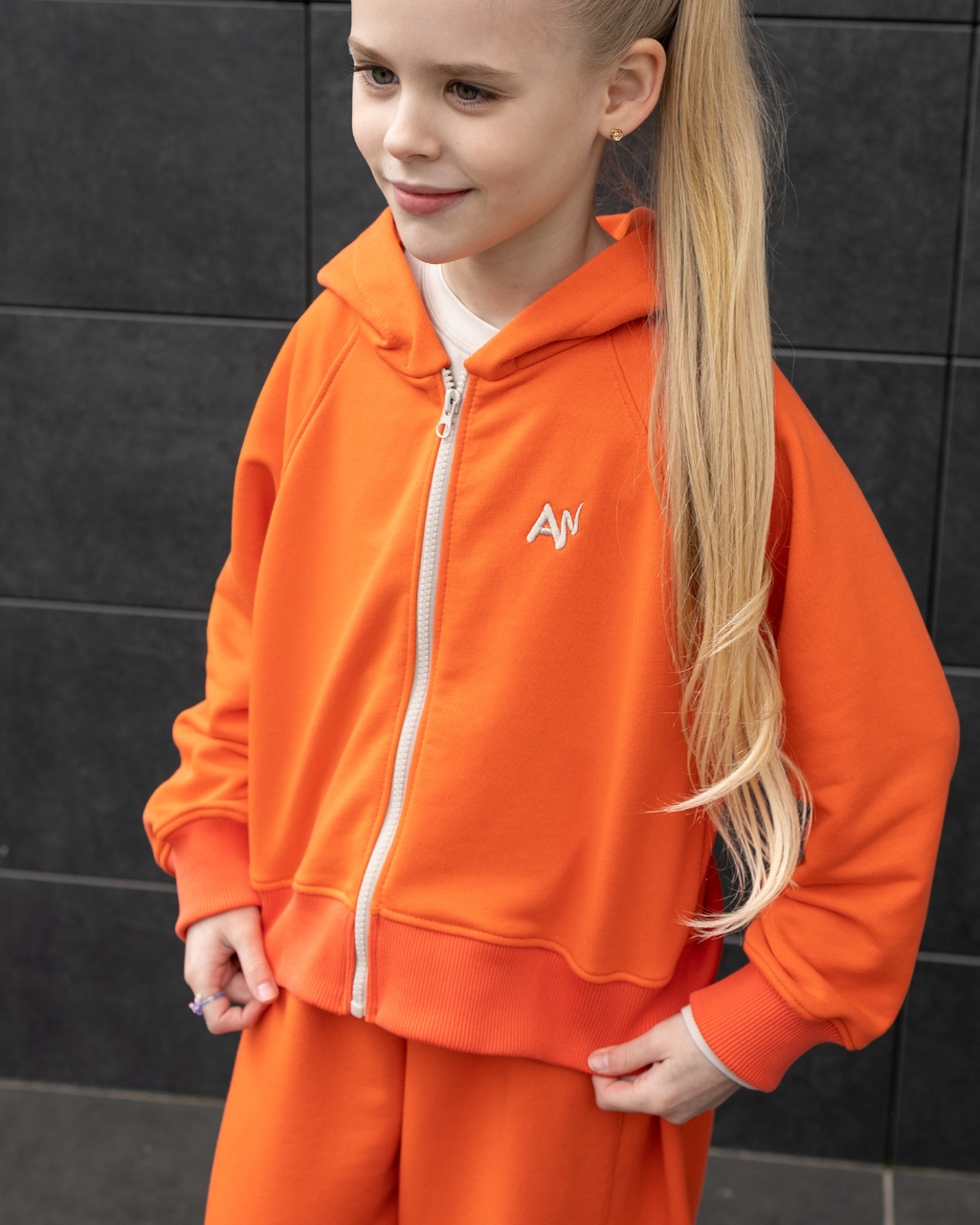 Front view of girl in bright orange hoodie Alwair Kids