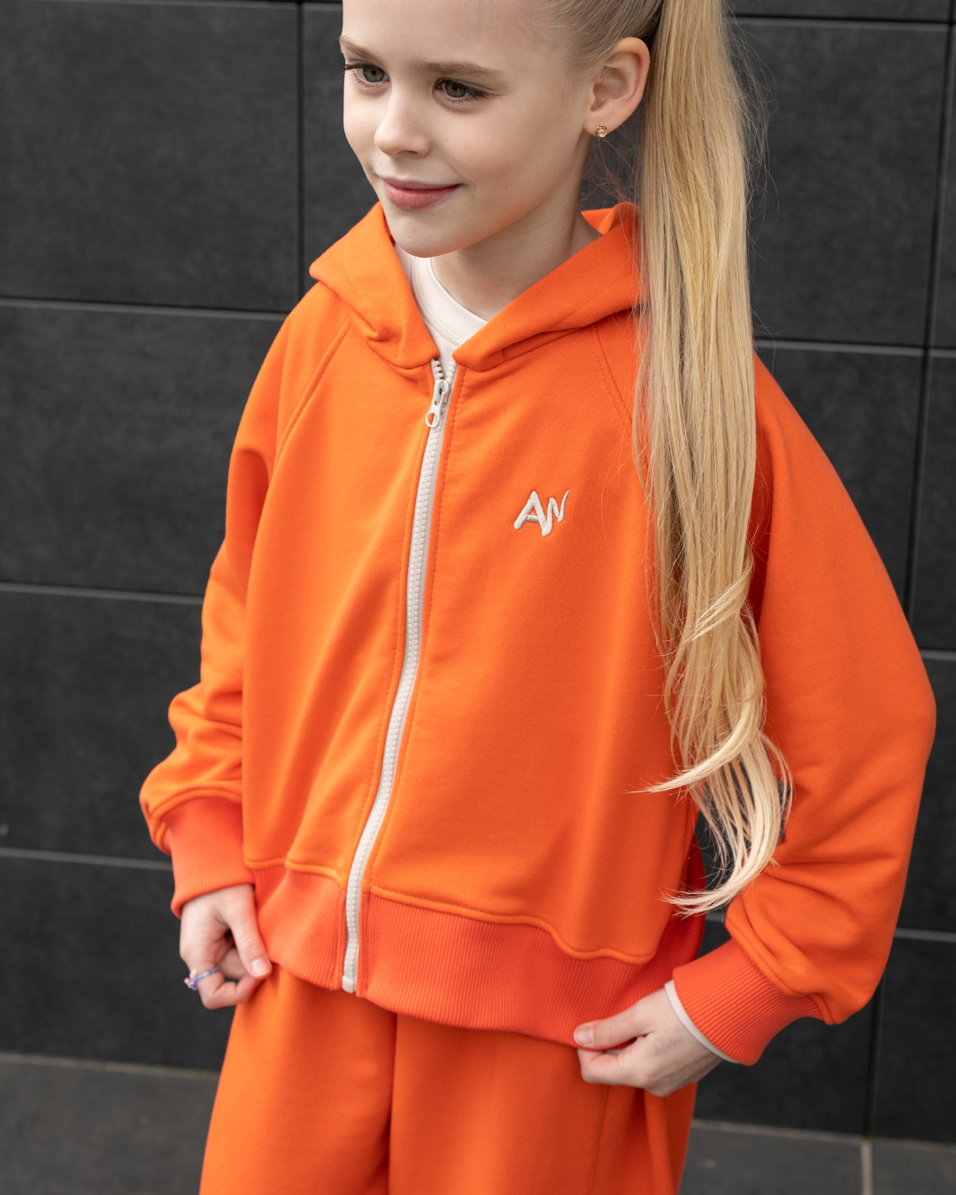 Front view of girl in bright orange hoodie Alwair Kids