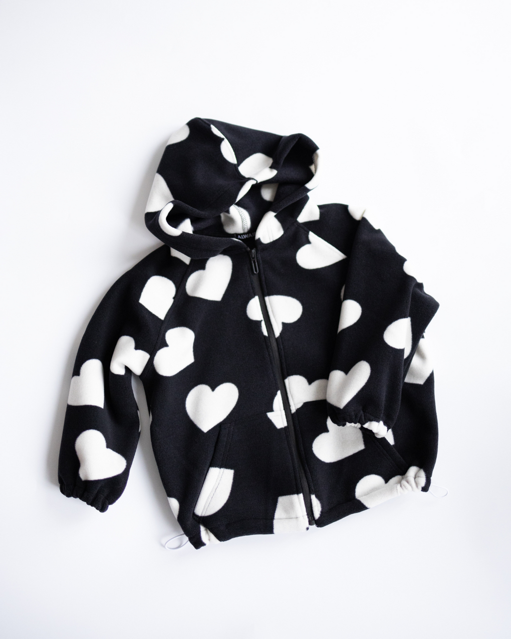 Black fleece zip hoodie with white hearts flat lay Alwair Kids