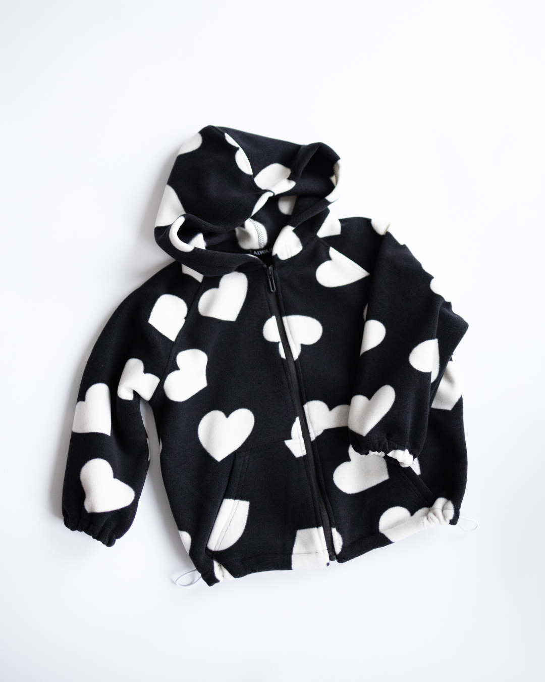Black fleece zip hoodie with white hearts flat lay Alwair Kids