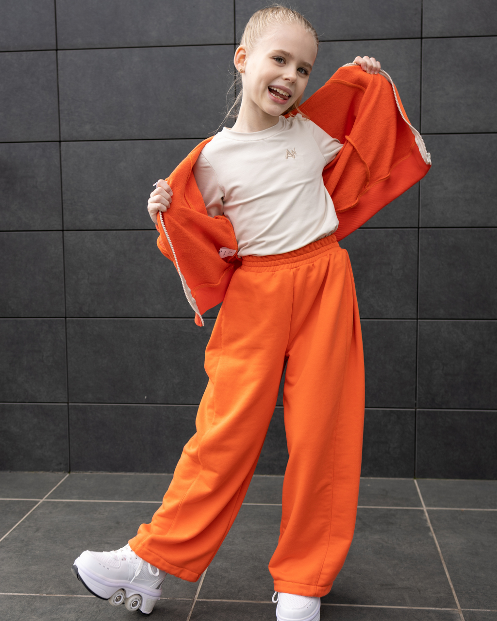 Active girl in Alwair Kids orange tracksuit showing long sleeve and drawstring pants