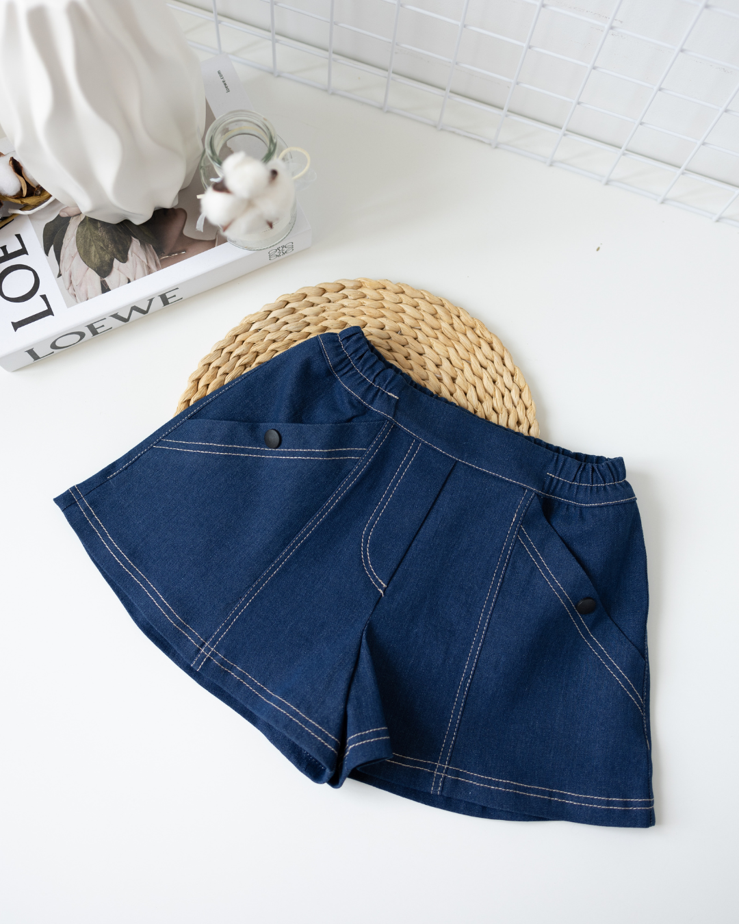 Flat lay of girls lightweight blue denim shorts with decorative buttons Alwair Kids