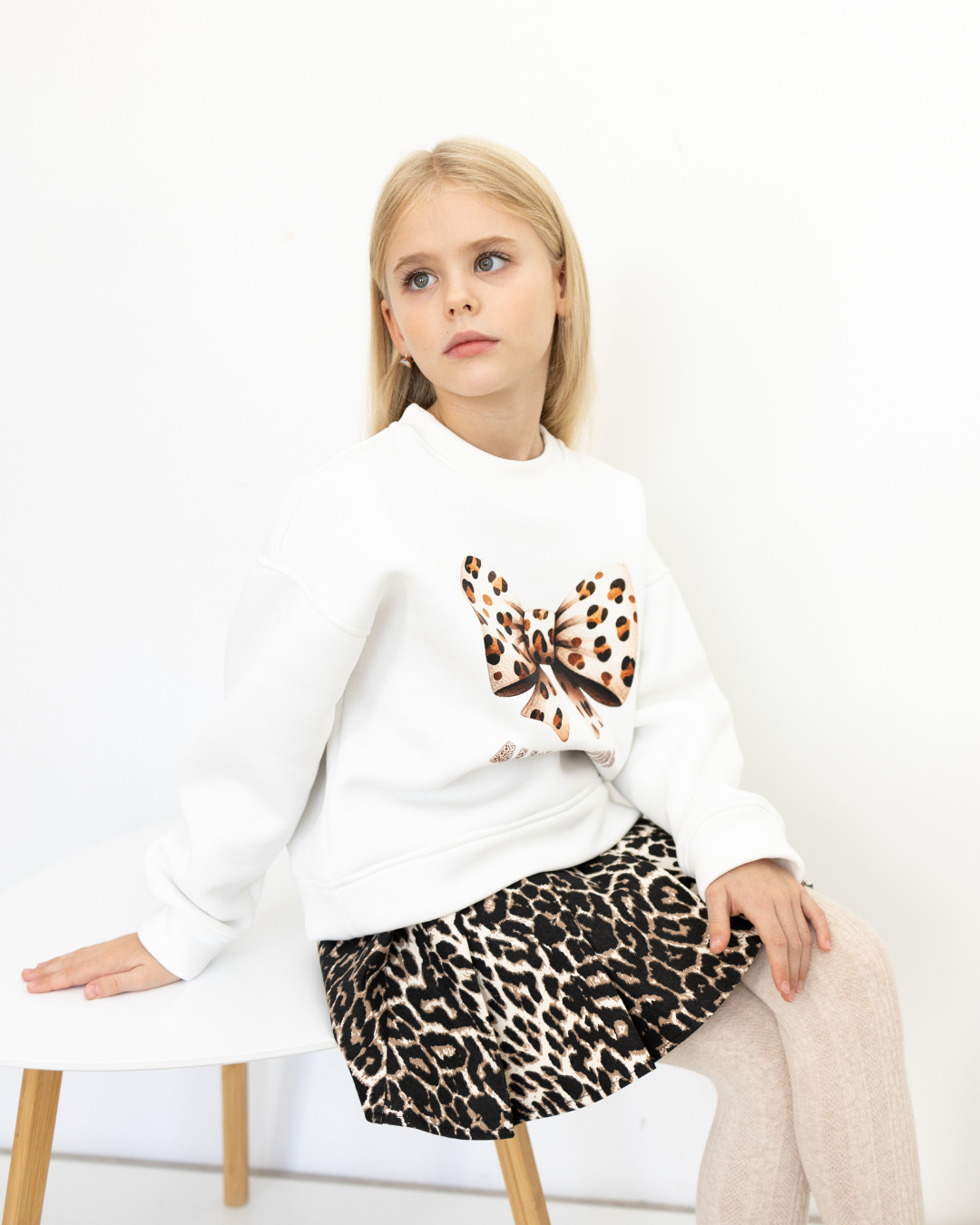 Side view of girl in white sweatshirt with leopard bow by Alwair Kids