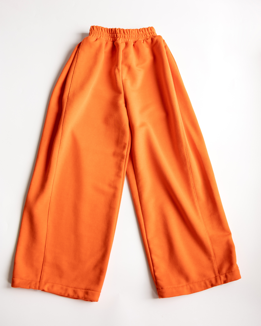 Flat lay of orange oversize kids pants with drawstring waist by Alwair Kids