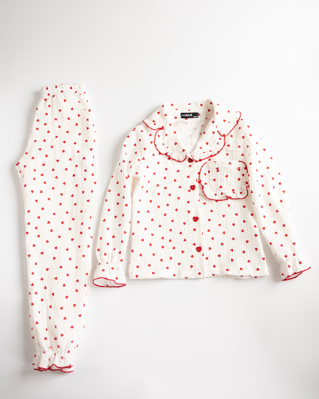 Girls' two-piece pajama set with ruffle trim and red heart print, laid flat