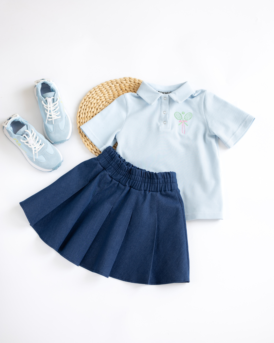 Tennis outfit flat lay with light blue polo and pleated denim skirt by Alwair Kids