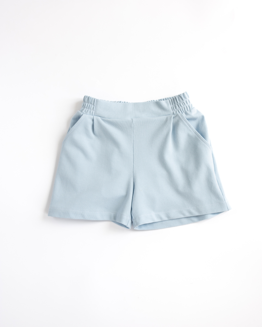 Flat lay blue lacoste girls shorts with elastic waistband and side pockets