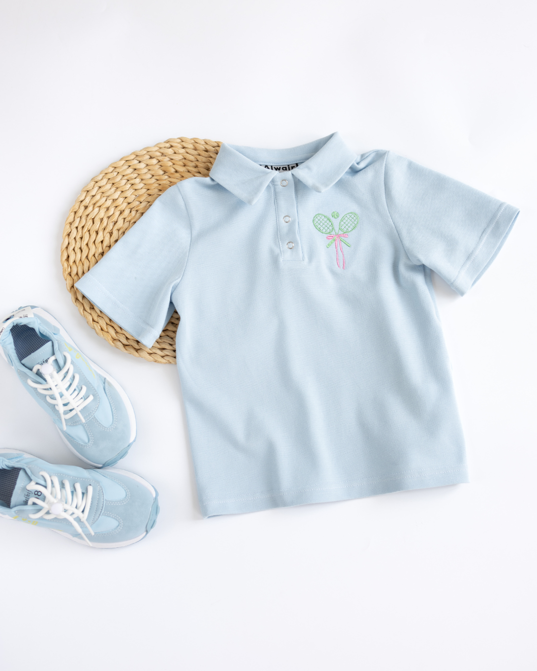 Flat lay of light blue Alwair Kids polo shirt with matching sneakers