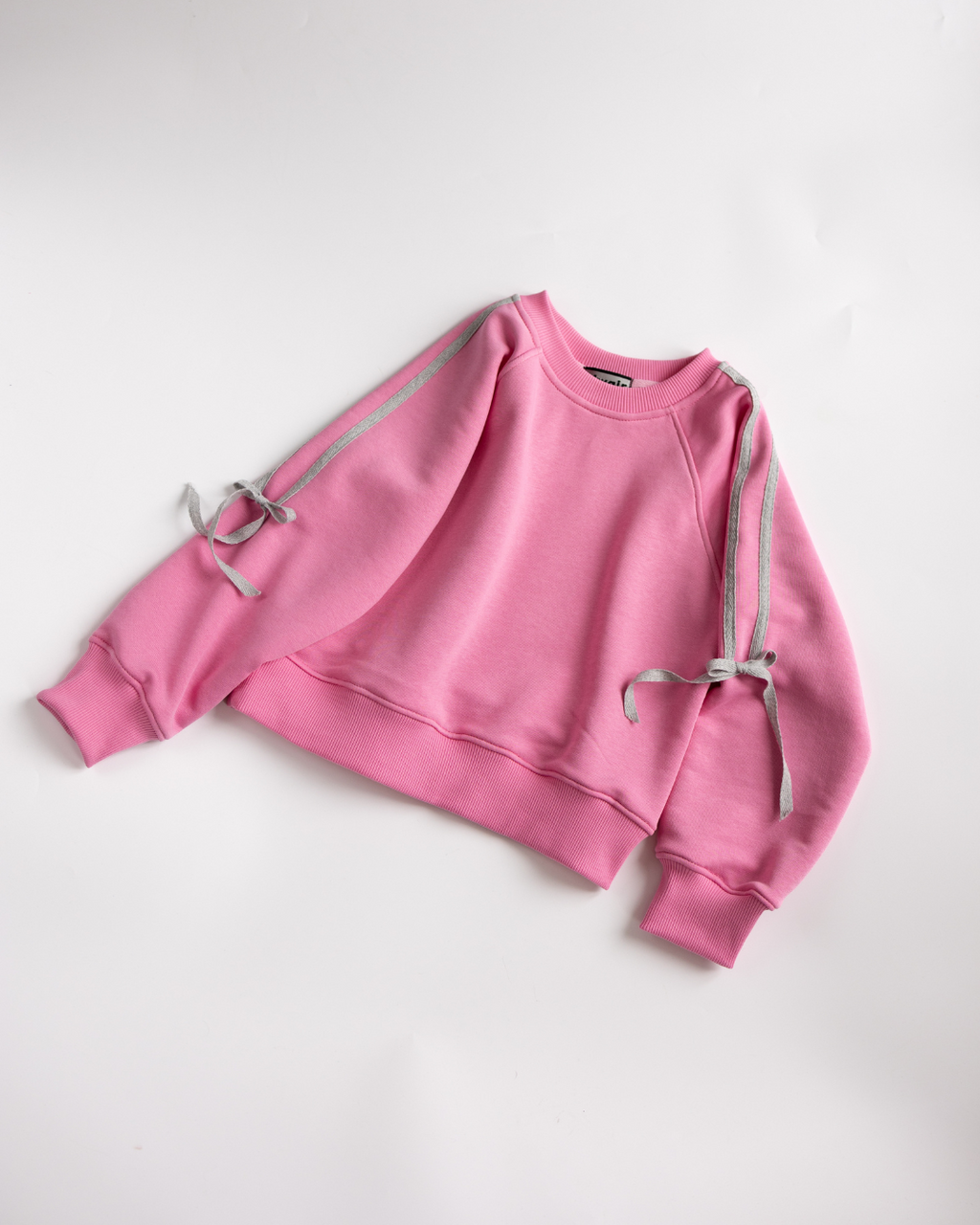 Flat lay of pink sweatshirt with silver bows on sleeves – Alwair Kids.
