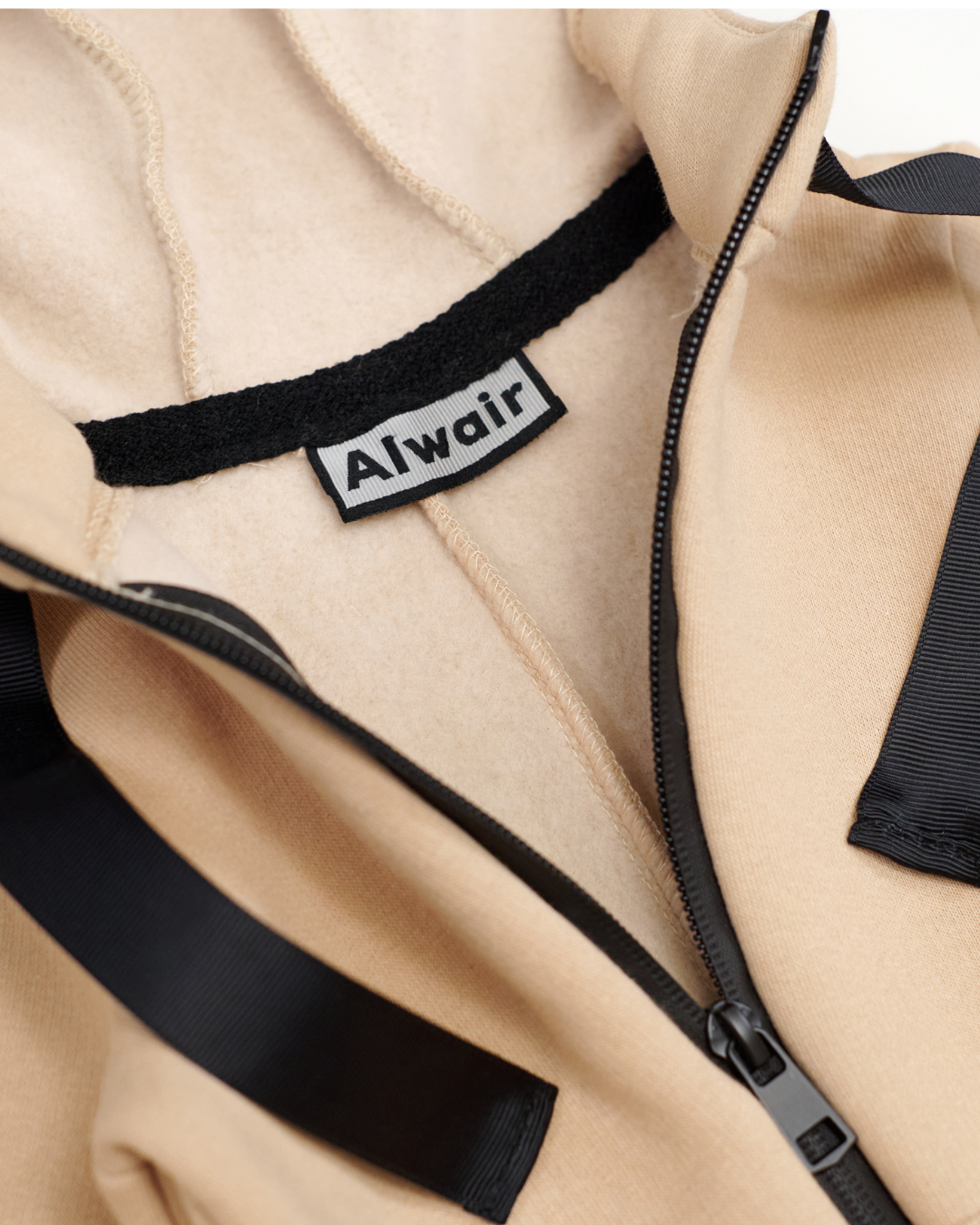 Close-up of Alwair brand label inside beige fleece kids jumpsuit
