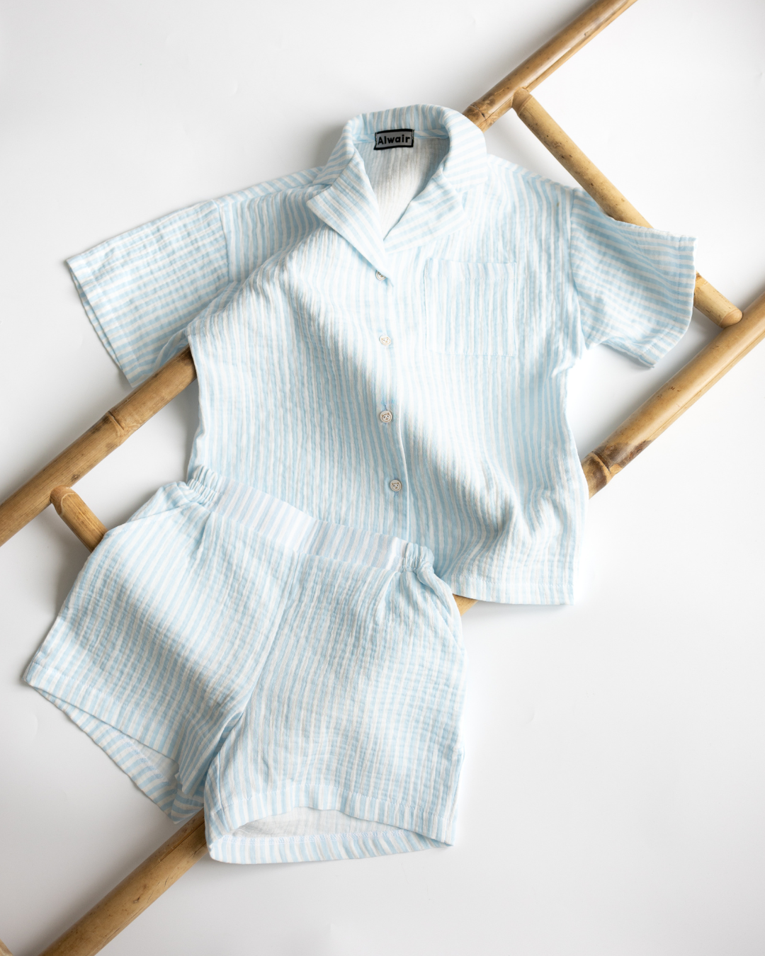 Flat lay of blue muslin summer set on bamboo for kids by Alwair Kids