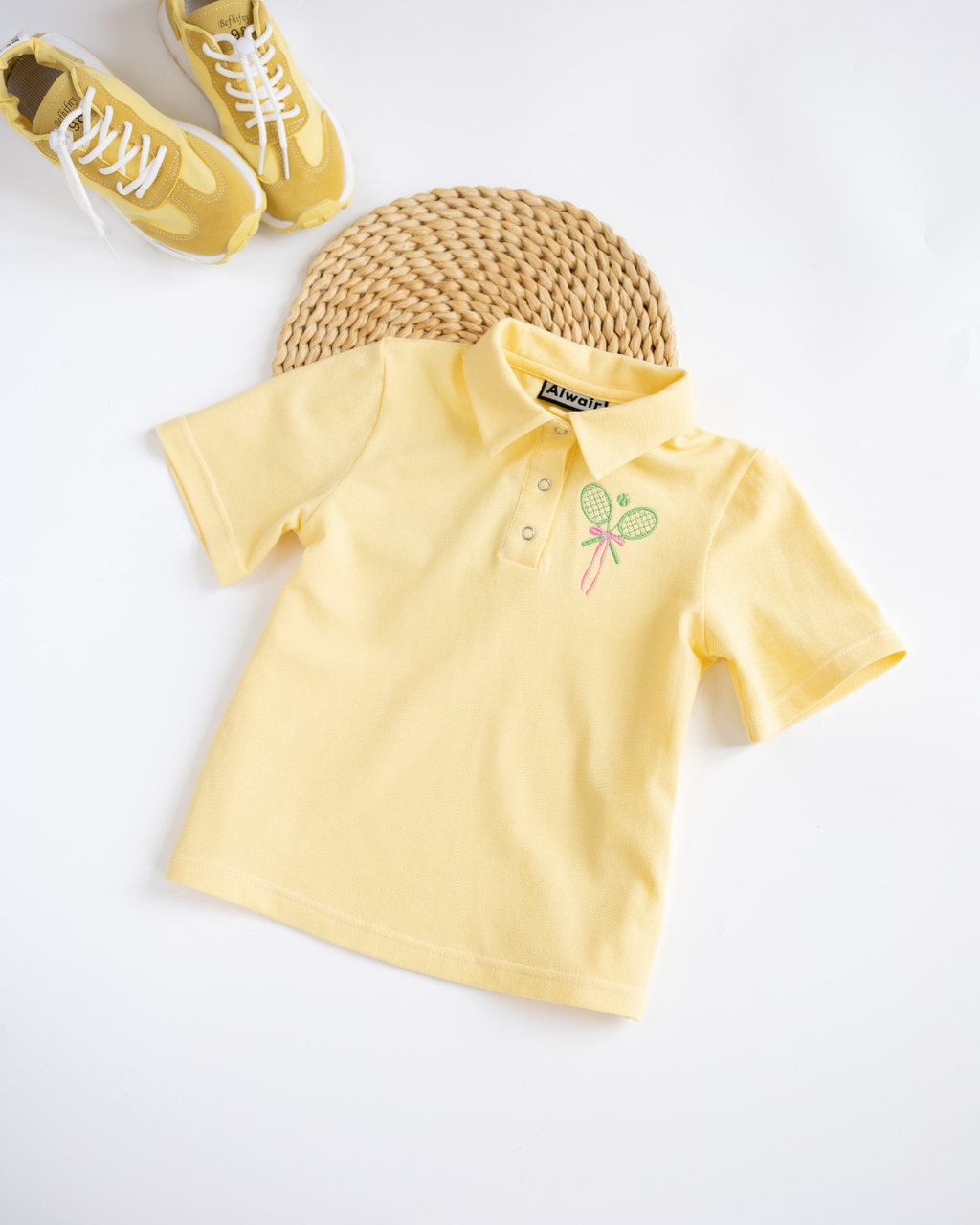 Flat lay of yellow Alwair Kids tennis polo shirt with yellow shoes