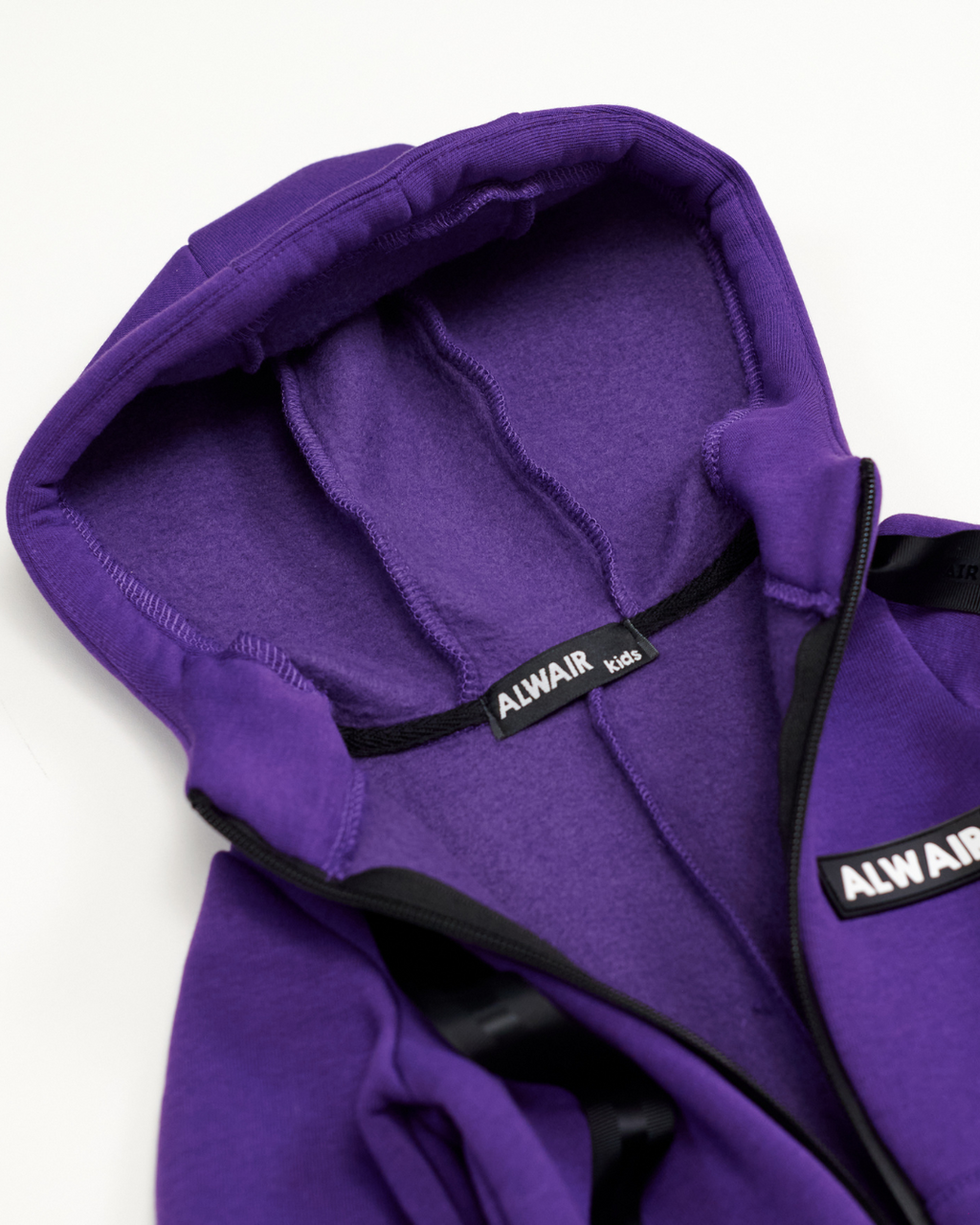 Interior view of hood and label on purple fleece jumpsuit by Alwair Kids