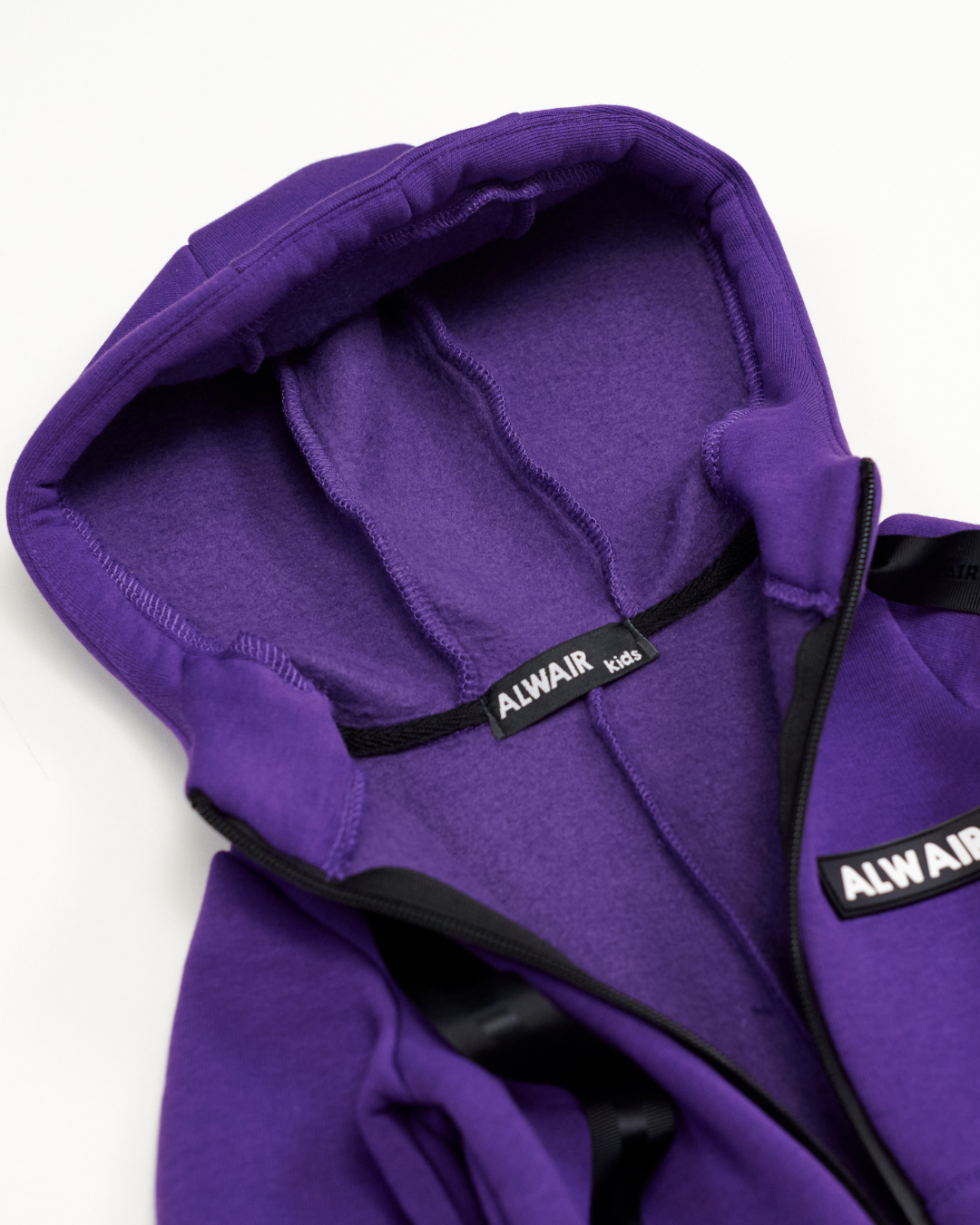 Interior view of hood and label on purple fleece jumpsuit by Alwair Kids
