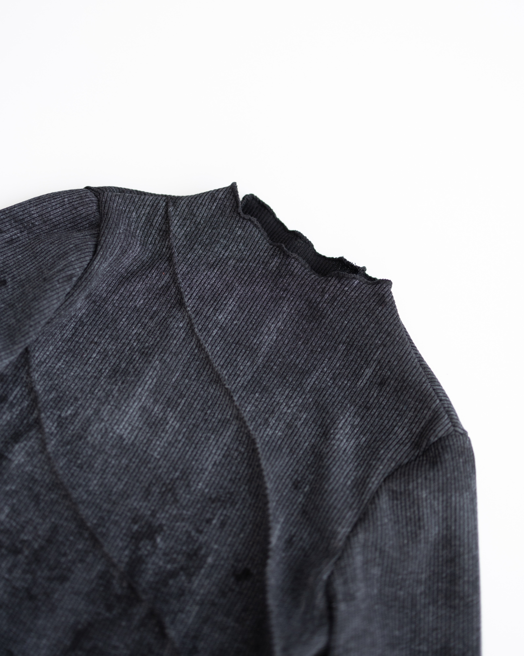 Close-up of neckline detailing and ribbed cotton fabric in black
