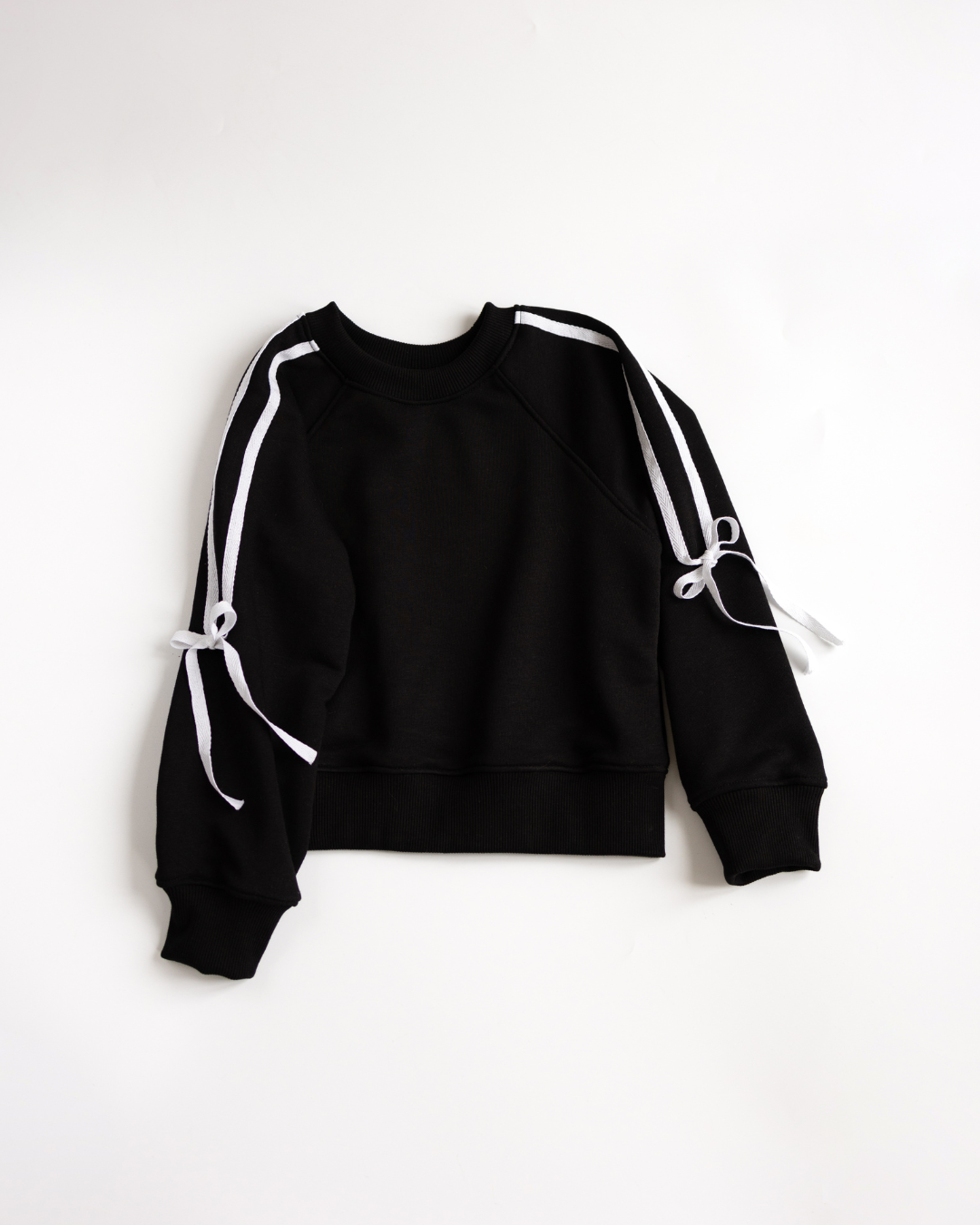 Black sweatshirt with white sleeve bows displayed flat on white background.