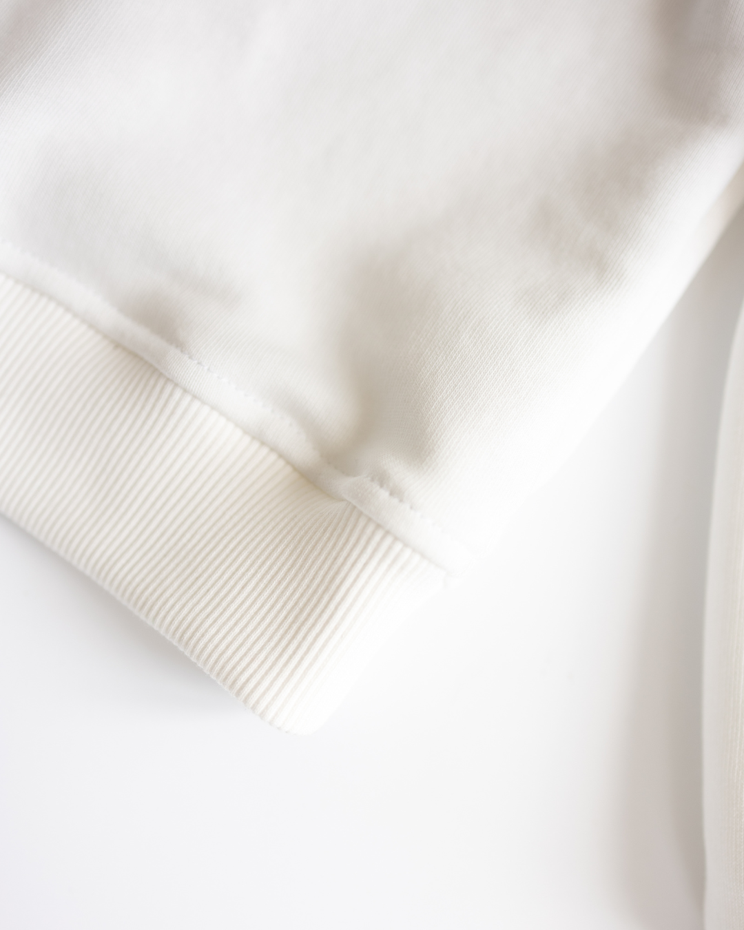Detailed view of ribbed hem on white cotton fleece sweatshirt
