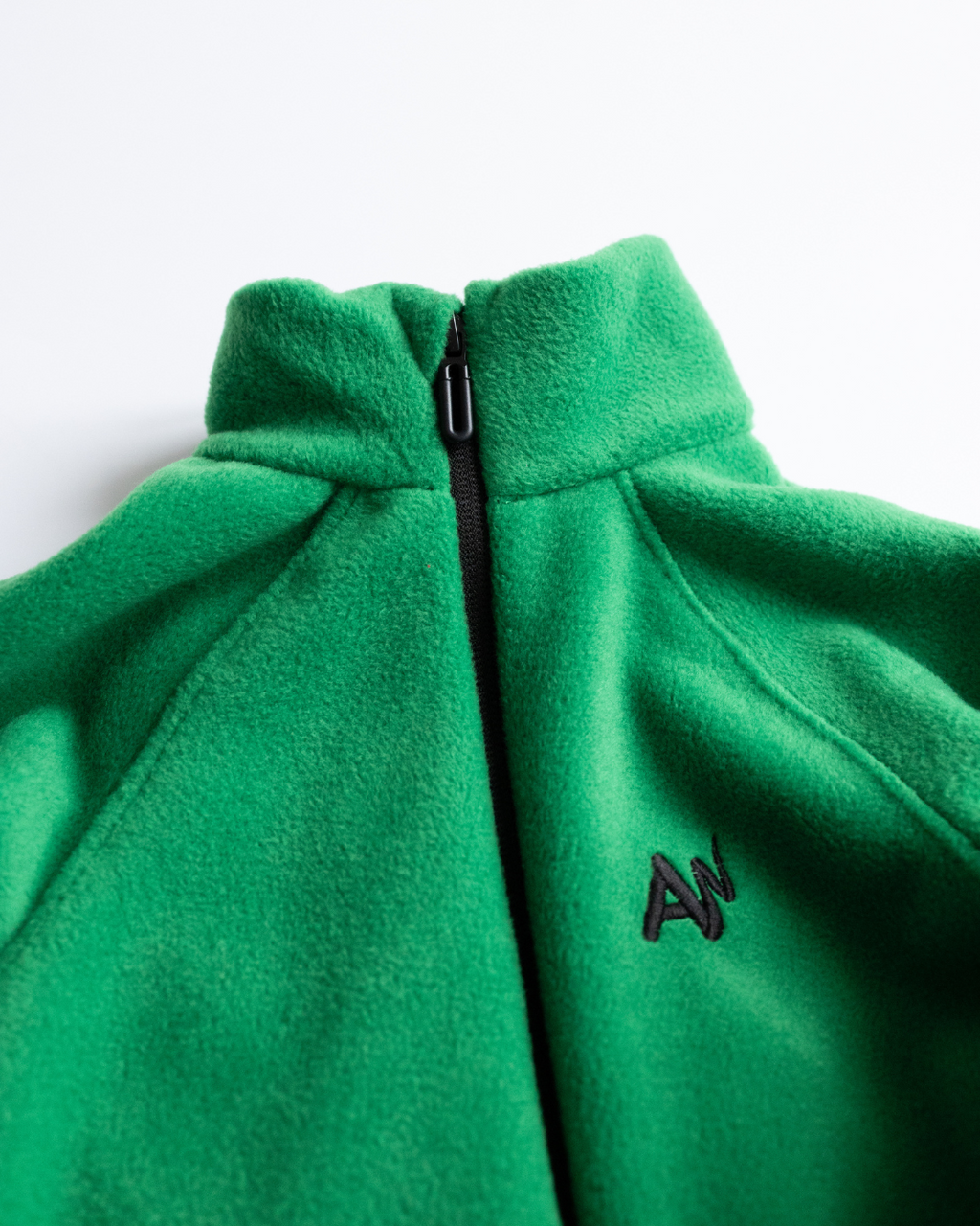 Close-up of high collar and AW embroidery on green fleece overall