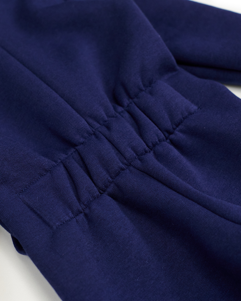 Elastic back detail on navy blue fleece jumpsuit showing growing-fit feature