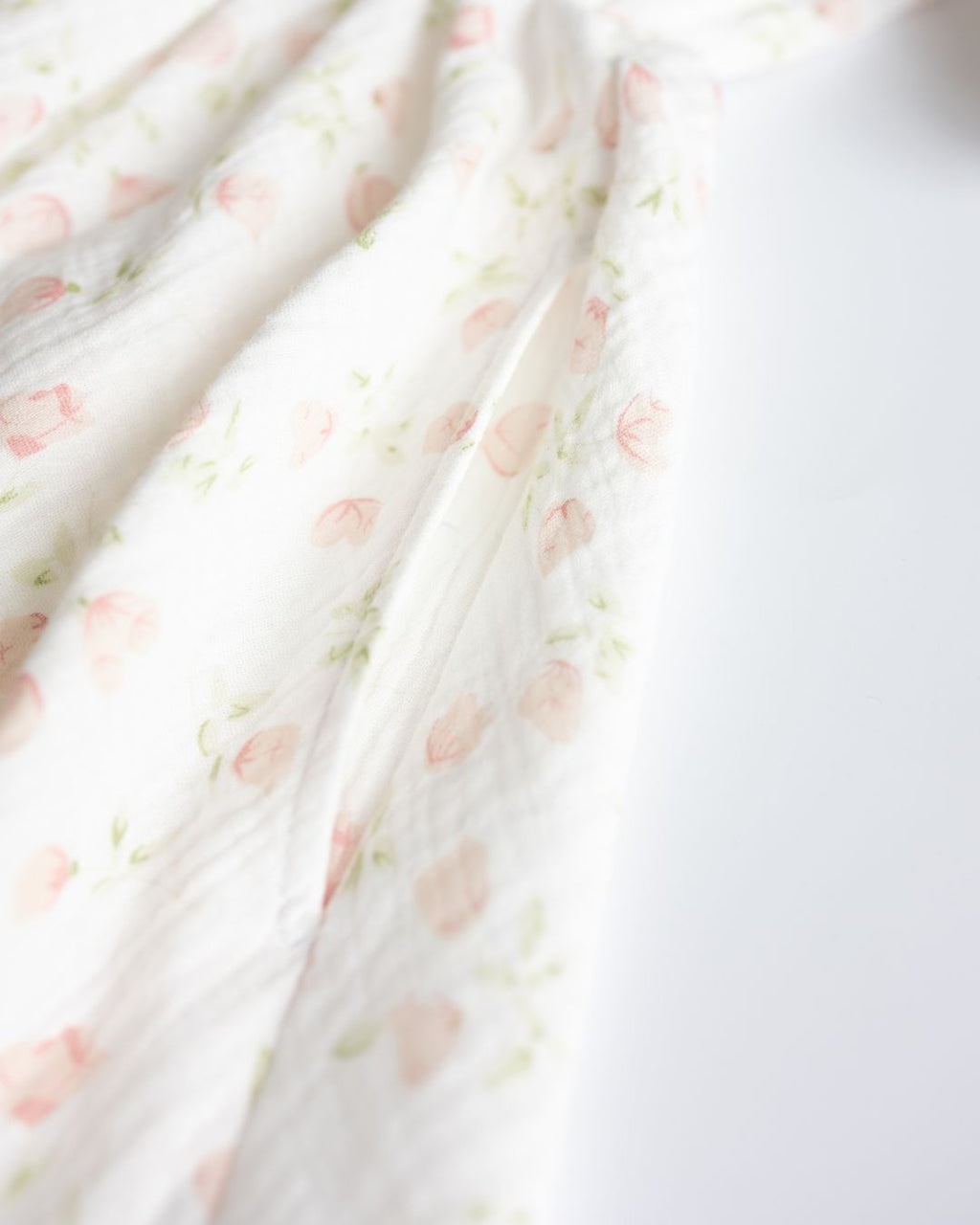 Soft white muslin fabric with pink floral print close-up