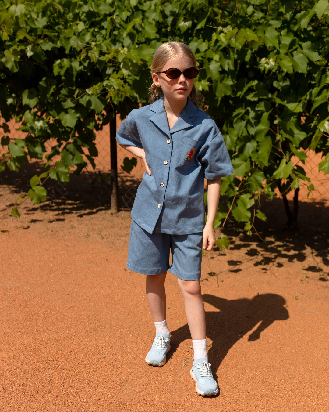 Girl wearing a denim summer set by Alwair Kids – relaxed-fit shirt and shorts with colorful capybara and watermelon print, perfect for stylish everyday comfort.