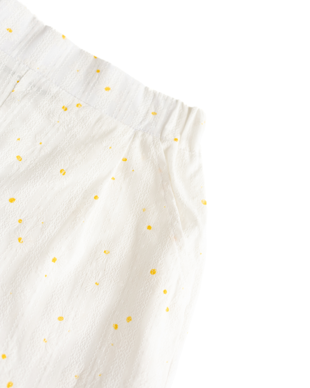 Close-up of soft elastic waistband and yellow floral print on white batiste shorts

