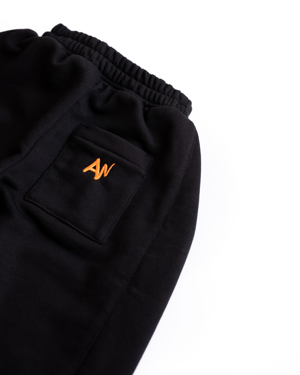 Close-up of back pocket with orange AN logo embroidery on black pants