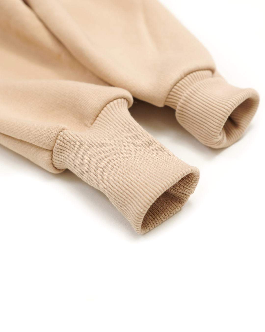 Ribbed cuff detail on sleeve of beige kids fleece jumpsuit for warmth and fit