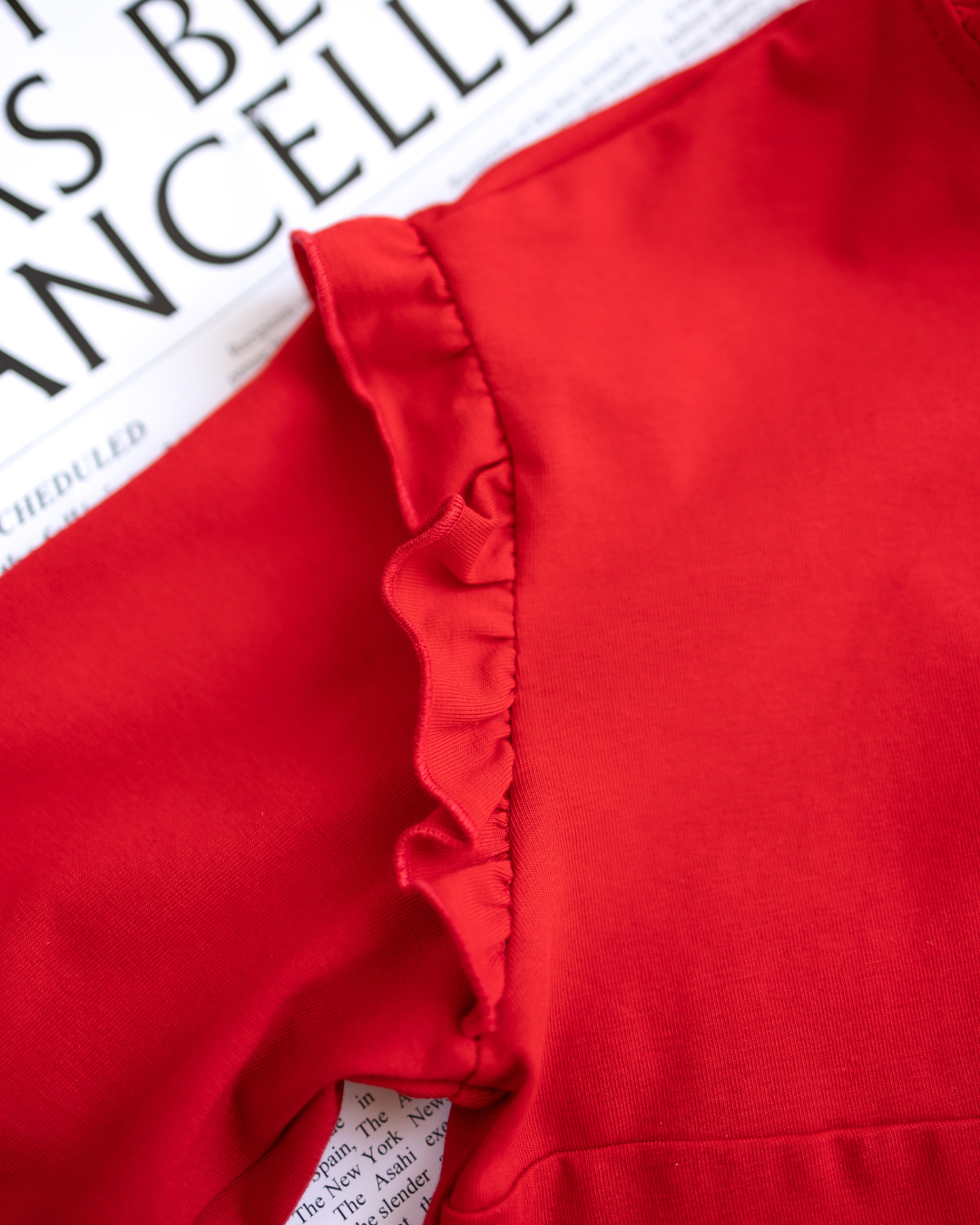 Close-up of shoulder ruffle detail on red cotton top for girls